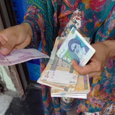 A visitor holds a handful of Iranian rial banknotes on a street in Ardabil, Iran"