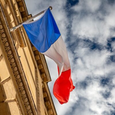 The French flag waves against a cloudy sky