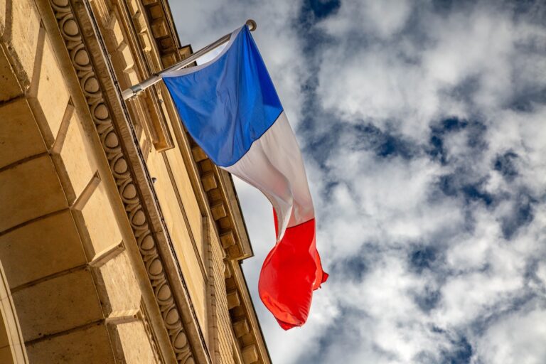 The French flag waves against a cloudy sky